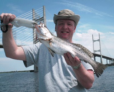 Angler holding a speckled trout in front of Jacksonville's Dames Point bridge on the St. Johns River